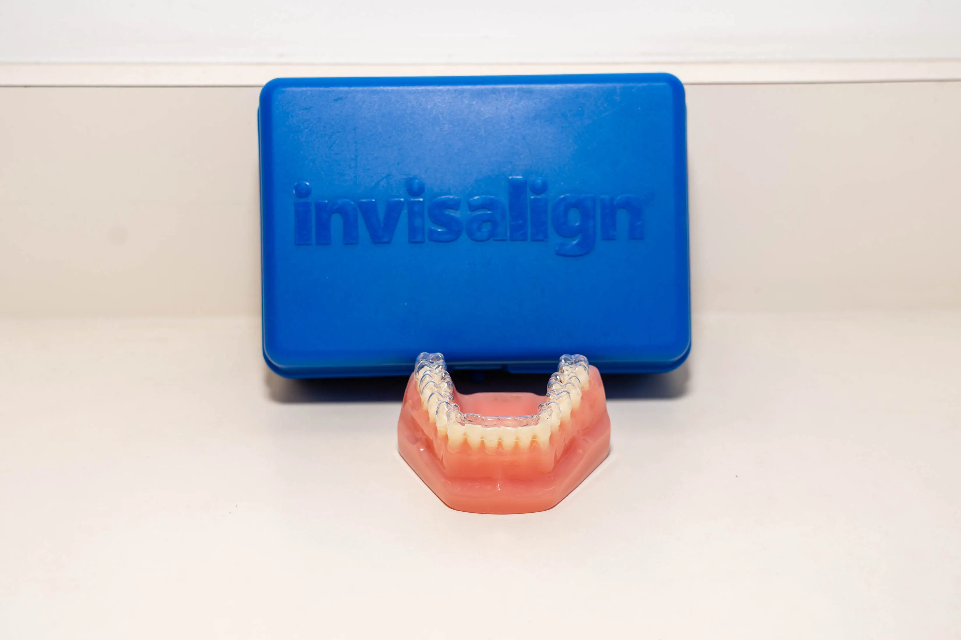 Blue box with a set of invisalign braces on top of it, sitting on a white surface