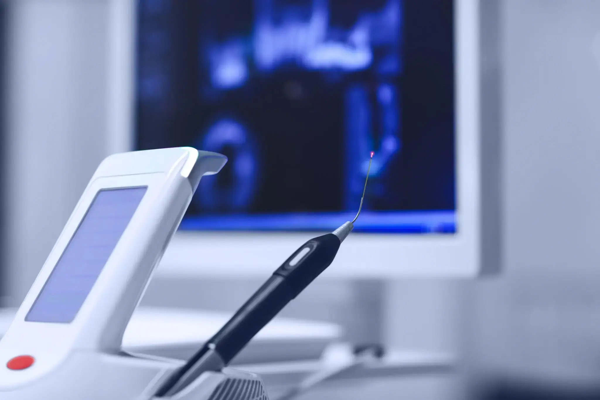 White and black electronic device sitting on top of a table next to a computer monitor