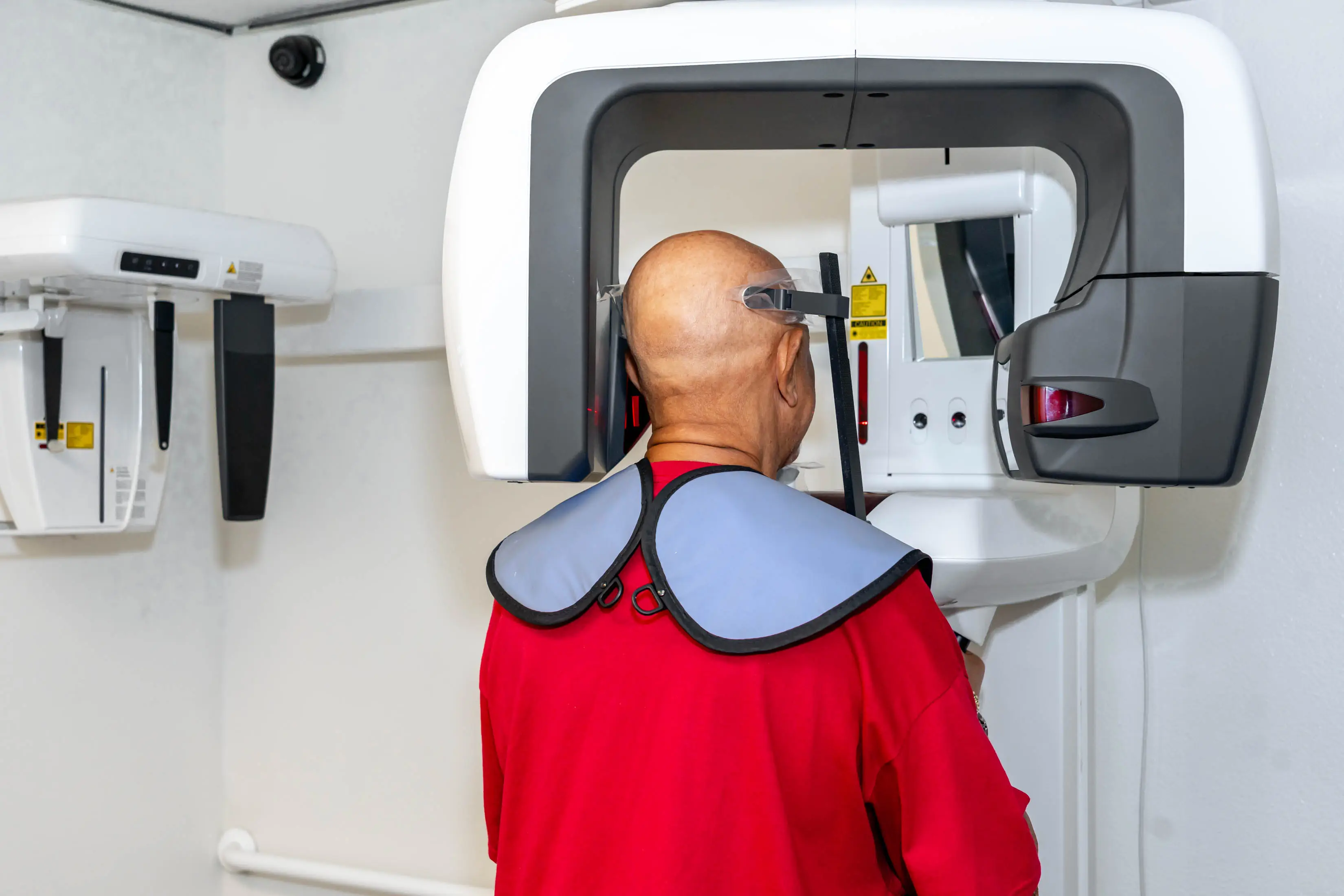 Man in a shirt standing in front of a MRI machine, with a wall in the background